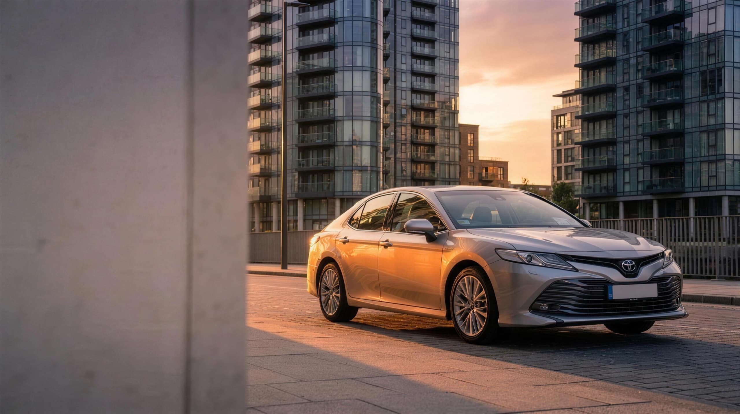 A clean private-hire saloon outside modern city apartments at golden hour